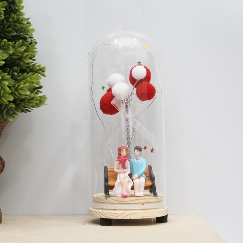 Couple Sitting On Bench With Balloons And Lights In Glass Shape Dome Showpiece